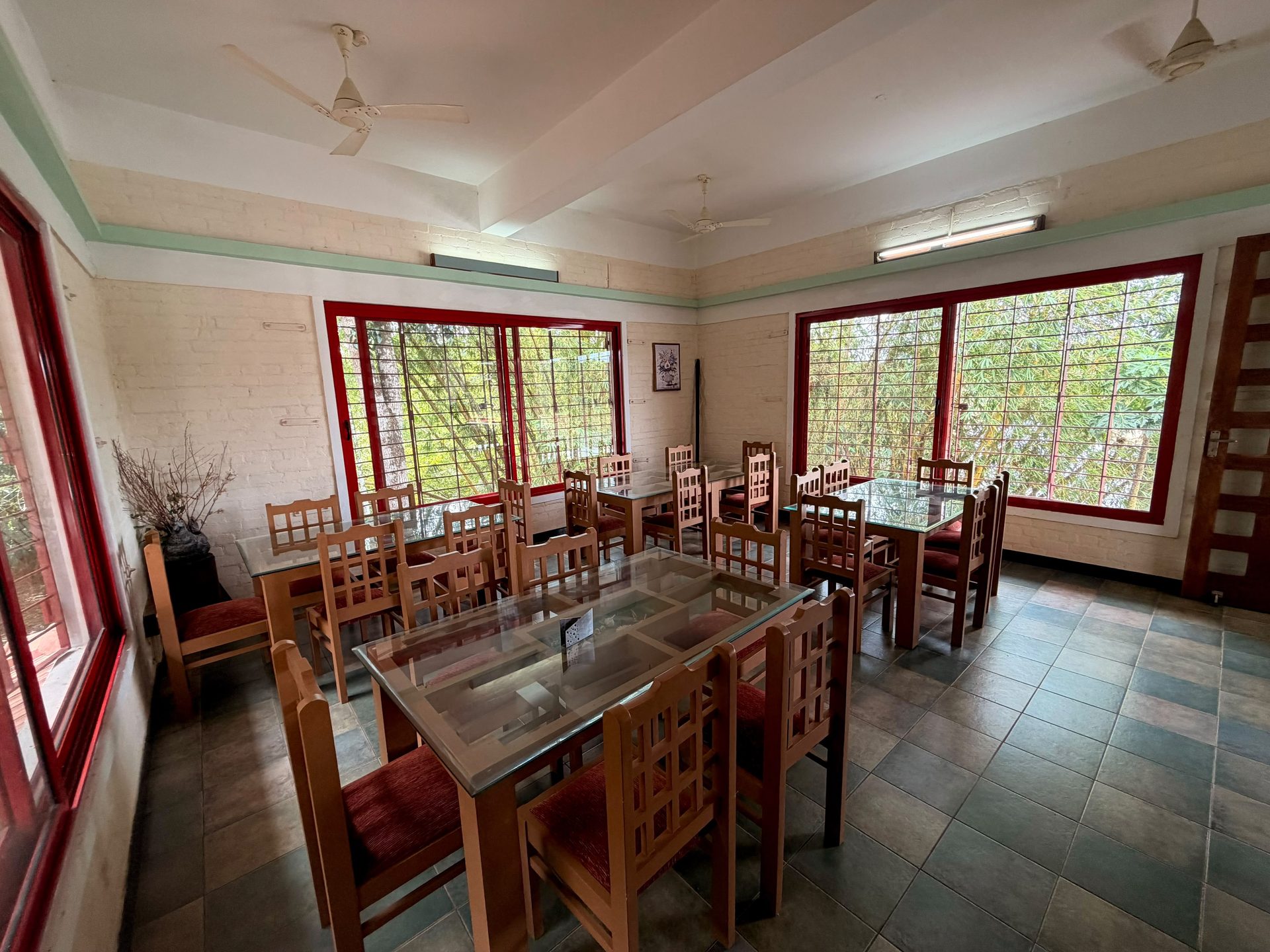 Dining hall with seating for groups, looking out to greenery